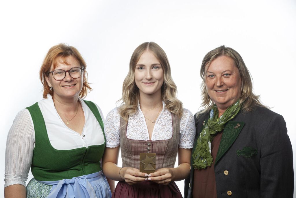 Drei Personen in bayerischer Tracht posieren lächelnd für ein Foto