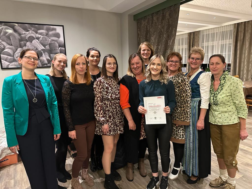 Eine Gruppe von Frauen steht zusammen und hält ein Zertifikat in den Händen, lächelnd und stolz